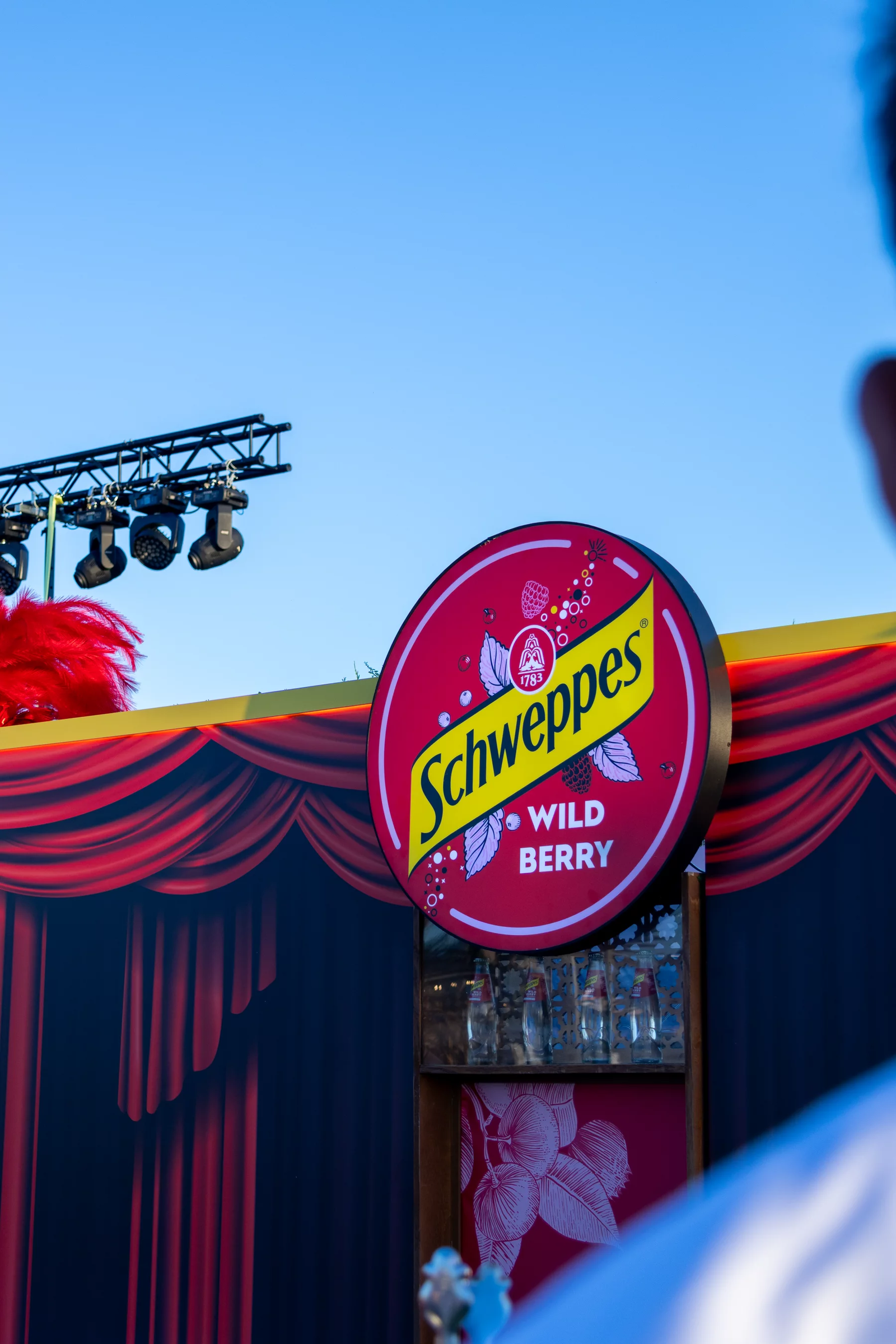 Cartel luminoso de Schweppes Wild Berry sobre una barra con cortinas rojas en Amarilla Night