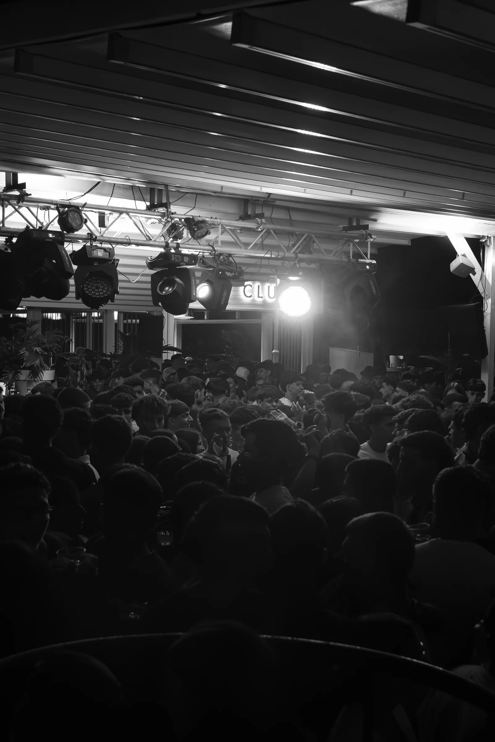Pista llena en una noche de Andana, en blanco y negro, bajo la estructura de luces y el rótulo del club