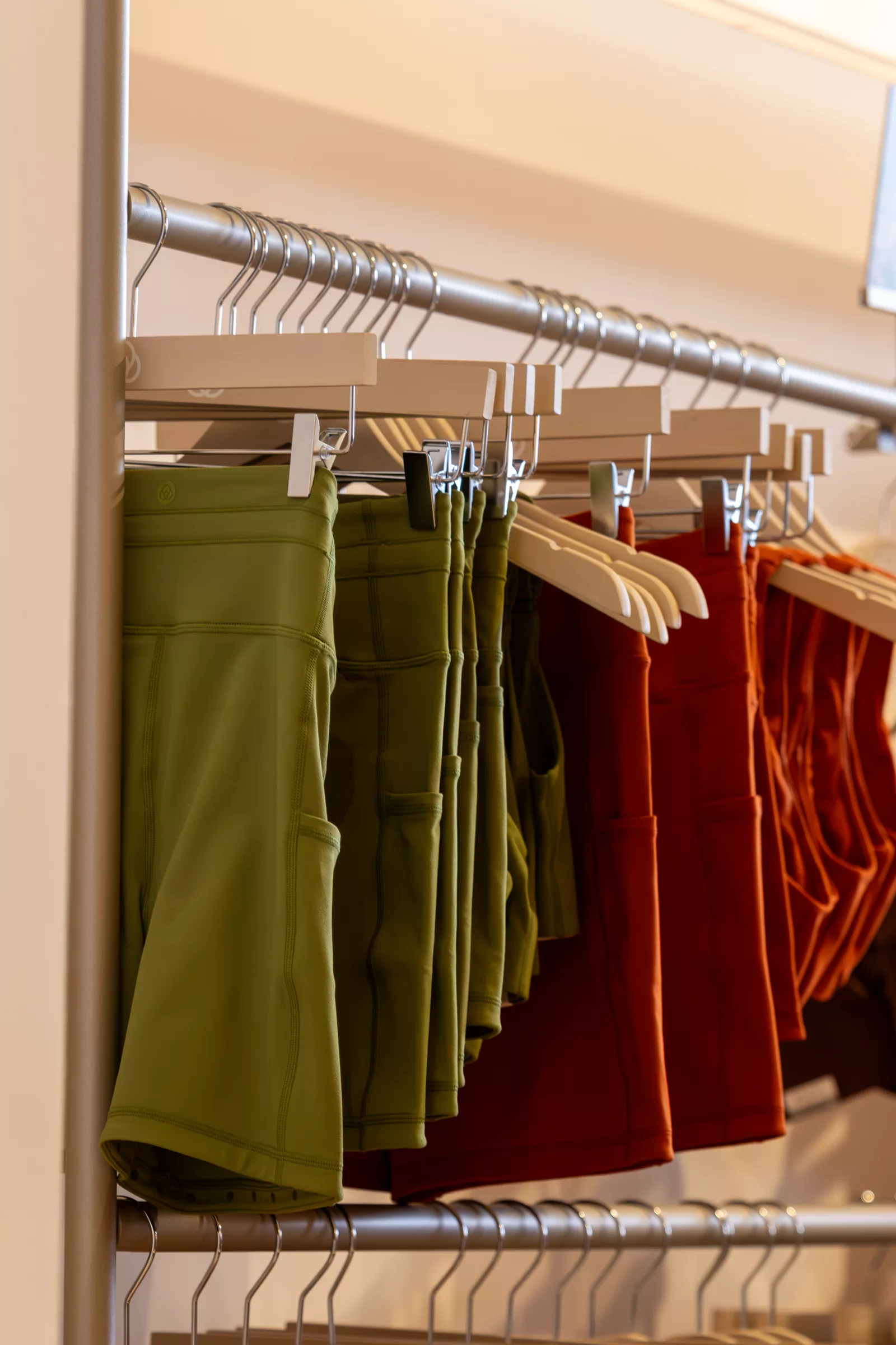 Perchas con prendas deportivas en verde oliva y rojo teja en la tienda de BSOUL