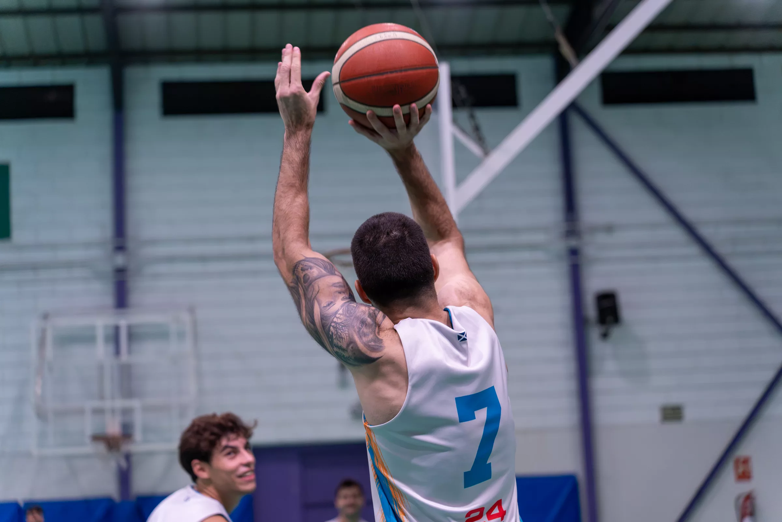 Jugador con el dorsal 7, de espaldas, levanta el balón para lanzar a canasta