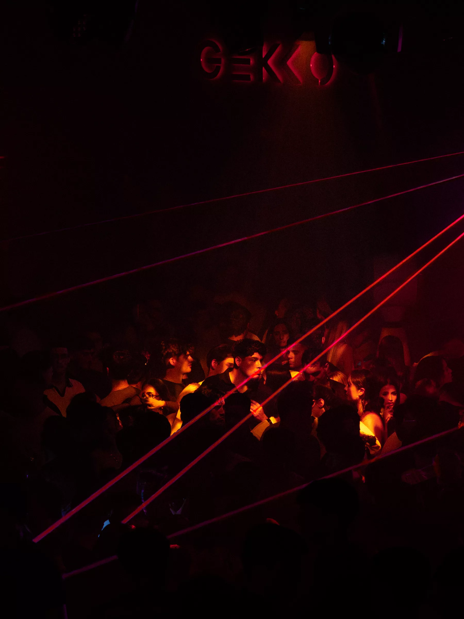 Láseres rojos cruzando la sala sobre el público de una discoteca a oscuras