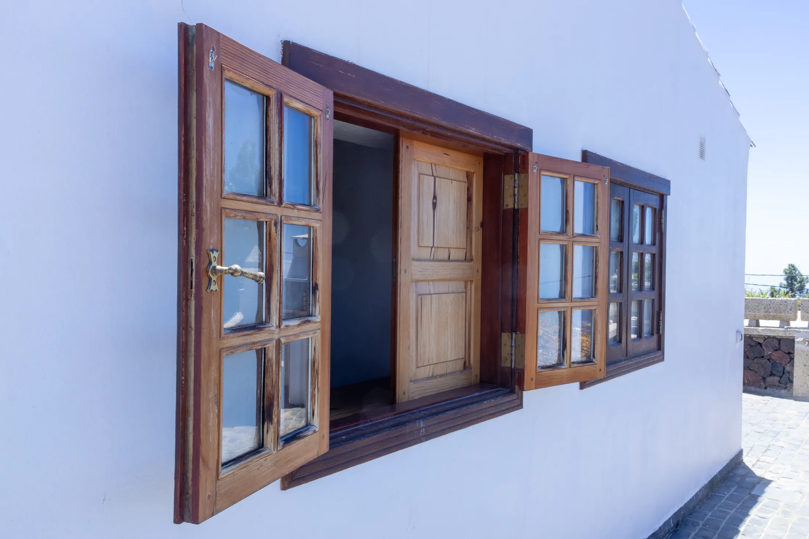Ventanas de madera abiertas en la fachada blanca de una vivienda de Finca Viñas